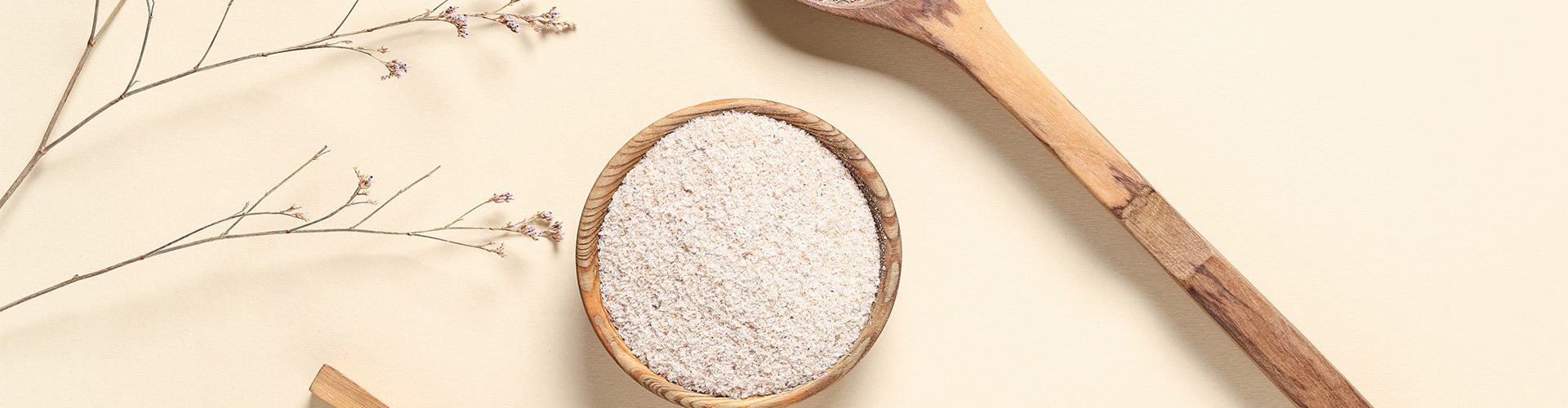 Colheres e tigela de madeira com fibras naturais em pó, representando alimentos ricos em fibras para o bom funcionamento do intestino.