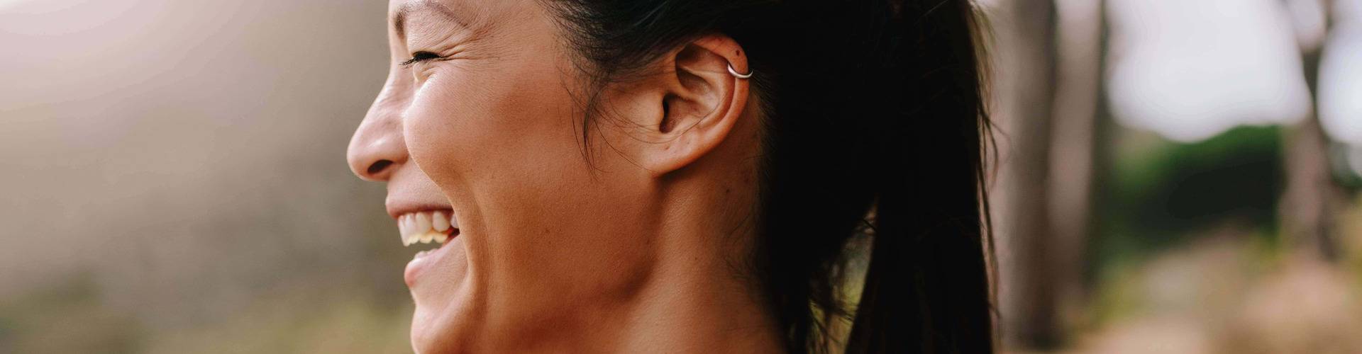 Mulher corredora sorri. Ela está de perfil com roupas esportivas pela manhã.