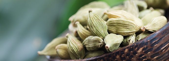sementes de cardamomo em uma pequena tigela com textura de madeira
