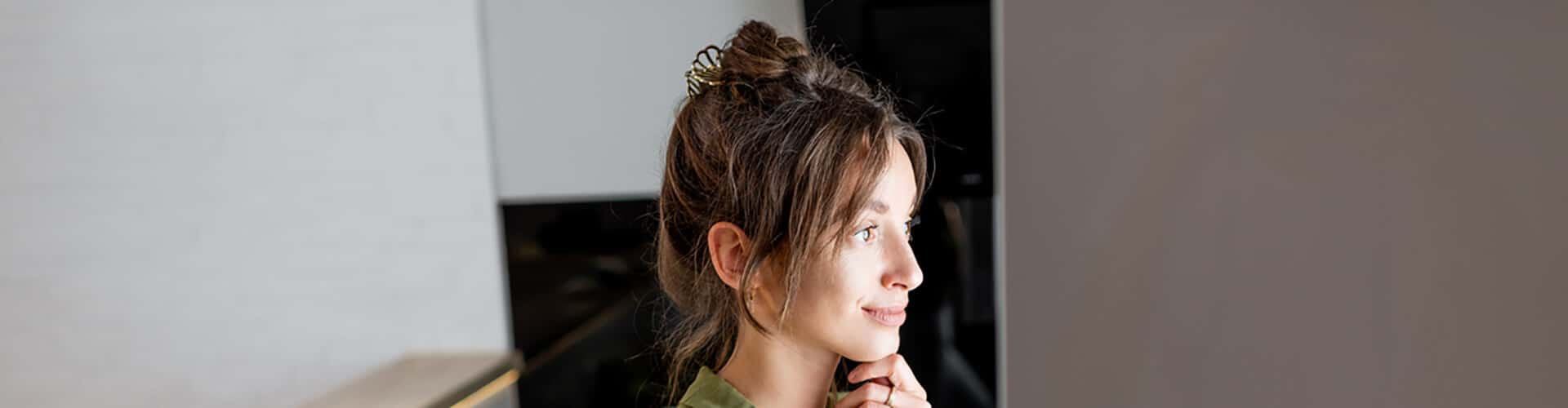 Mulher de perfil, olhando para a geladeira aberta na cozinha de casa.