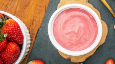 iogurte de morango visto de cima. Ao lado, uma tigela de morangos