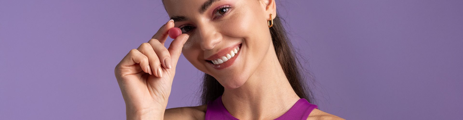 mulher segurando creatina em goma enquanto sorri